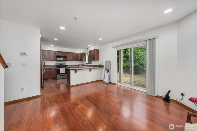 a view of kitchen with granite countertop stainless steel appliances and wooden floor