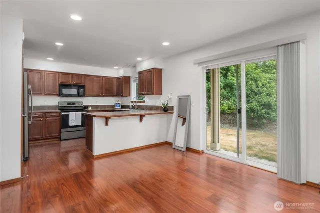 a kitchen with stainless steel appliances granite countertop a refrigerator a stove top oven a sink and a large window