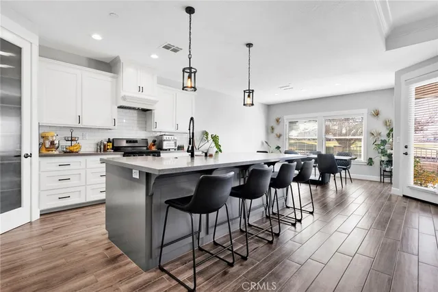 a kitchen with stainless steel appliances kitchen island granite countertop a table chairs and a refrigerator