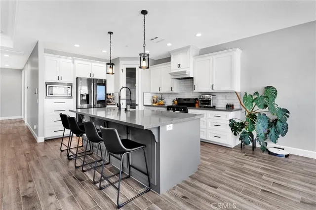 a kitchen with stainless steel appliances kitchen island a refrigerator a stove a sink and a dining table with wooden floor