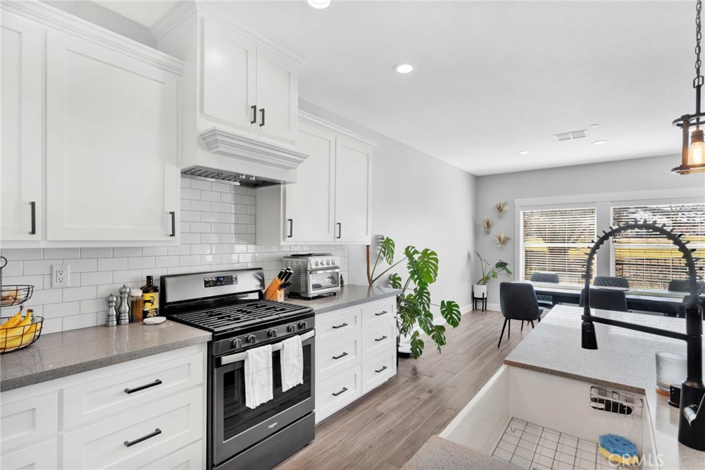12634 Spring Valley Parkway Victorville, CA 92395 - Photo 20 of 42 a kitchen with stainless steel appliances a stove a sink a counter space and cabinets