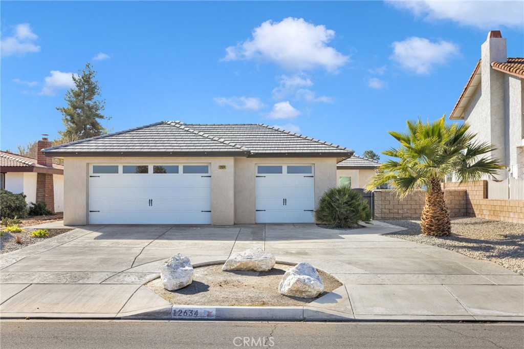 12634 Spring Valley Parkway Victorville, CA 92395 - Photo 2 of 42 a front view of a house with a yard and garage