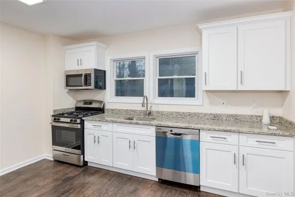 a kitchen with stainless steel appliances granite countertop a stove a sink and white cabinets