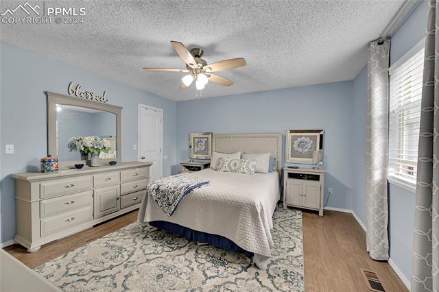5255 Pinon Valley Road Colorado Springs, CO 80919 - Photo 18 of 47 Bedroom featuring ceiling fan, light hardwood / wood-style floors, and a textured ceiling