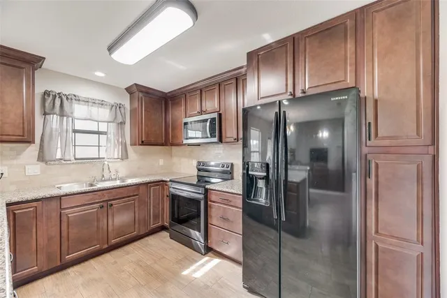 a kitchen with stainless steel appliances granite countertop a refrigerator and a sink