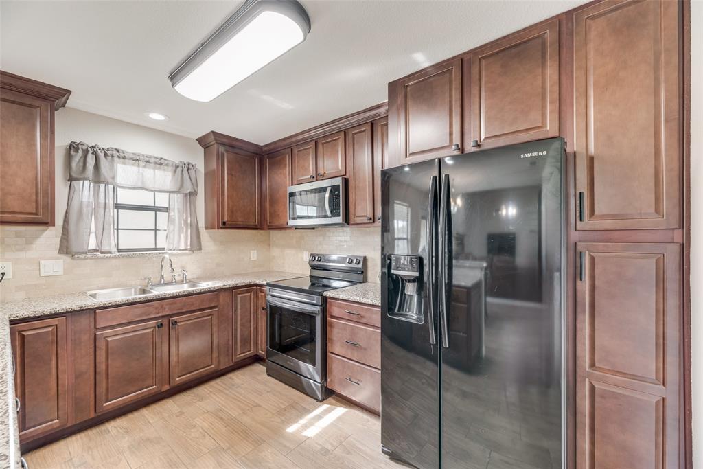 613 Torero Trail Oak Point, TX 75068 - Photo 26 of 32 a kitchen with stainless steel appliances granite countertop a refrigerator and a sink