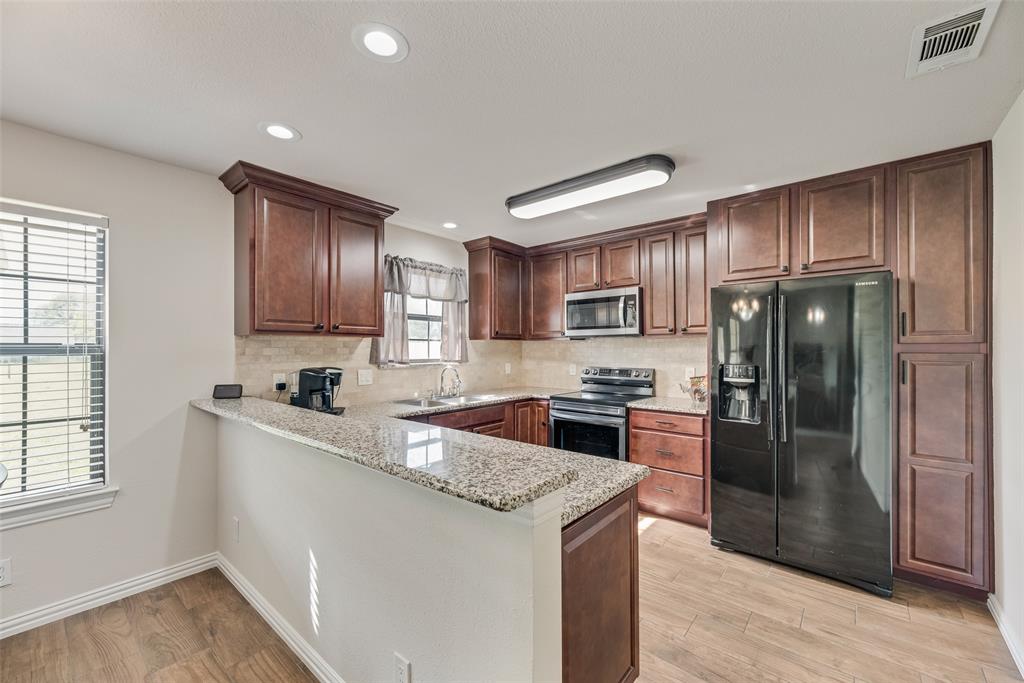 613 Torero Trail Oak Point, TX 75068 - Photo 4 of 32 a kitchen with granite countertop stainless steel appliances cabinets a sink and a window