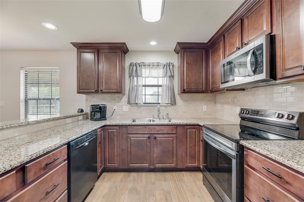 613 Torero Trail Oak Point, TX 75068 - Photo 5 of 32 a kitchen with stainless steel appliances granite countertop a sink stove and cabinets