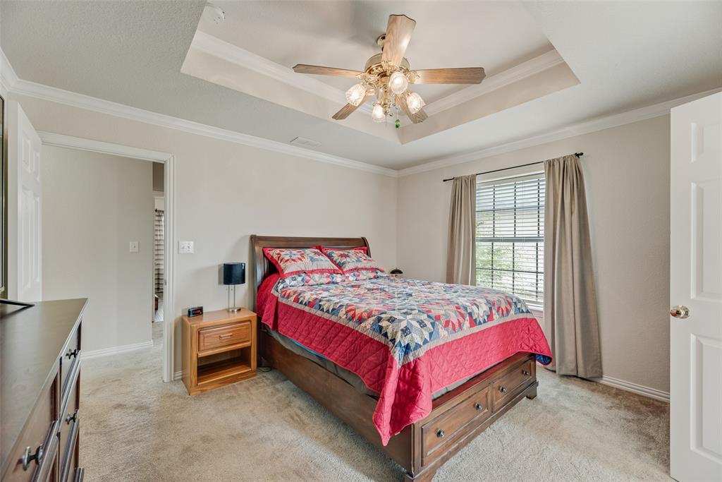 613 Torero Trail Oak Point, TX 75068 - Photo 9 of 32 a bedroom with a bed and a chandelier
