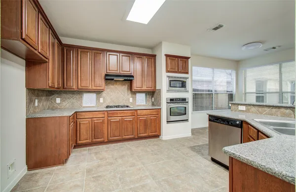 a kitchen with stainless steel appliances granite countertop a sink counter space cabinets and a large window