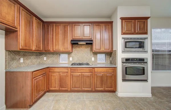 a kitchen with stainless steel appliances granite countertop a stove a sink dishwasher and a microwave oven with cabinets