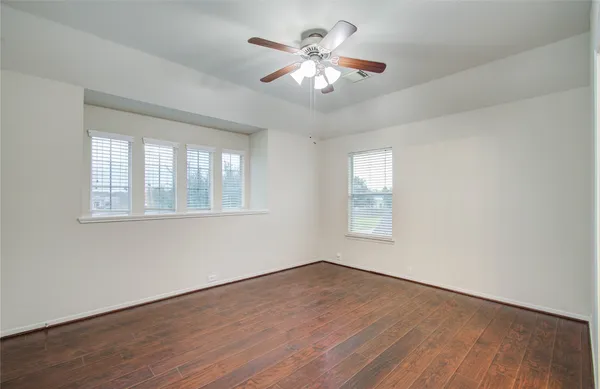 a view of an empty room with a window and wooden floor