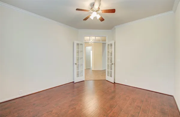 a view of empty room with wooden floor and fan