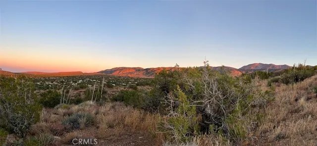 a view of mountain with sunset in background