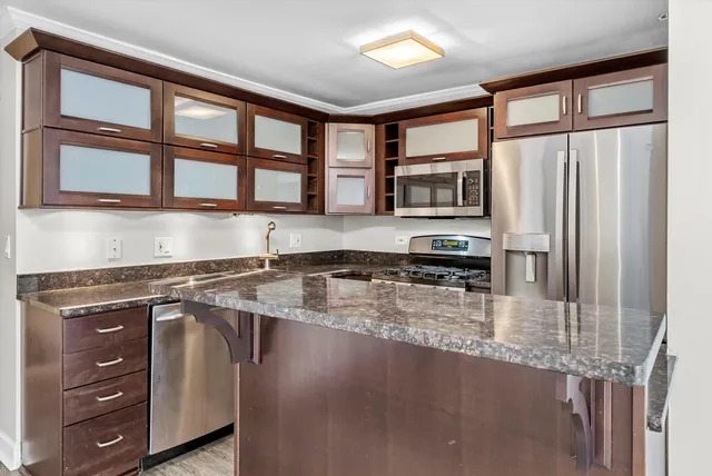a kitchen with stainless steel appliances granite countertop a stove a sink and a microwave