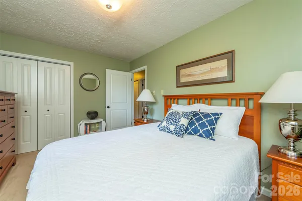 a bedroom with a bed and a lamp on dresser