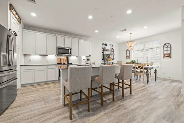 a kitchen with a dining table chairs refrigerator and cabinets