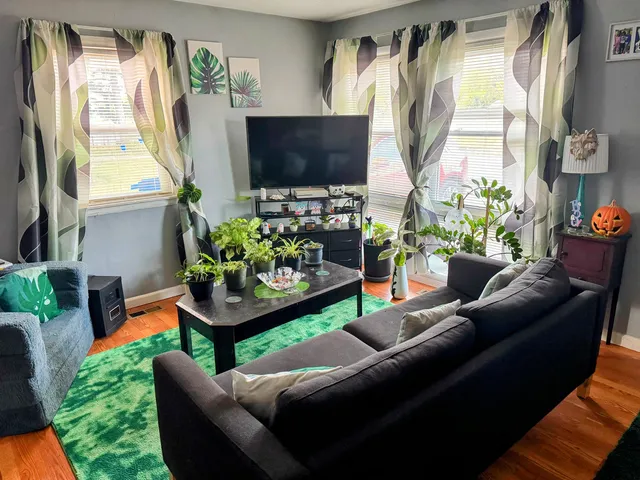 a living room with furniture a flat screen tv and a floor to ceiling window