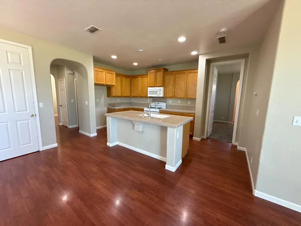 a kitchen with stainless steel appliances granite countertop a refrigerator a sink dishwasher and a stove with wooden floor