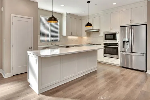 a kitchen with stainless steel appliances granite countertop a sink a stove a refrigerator and a microwave