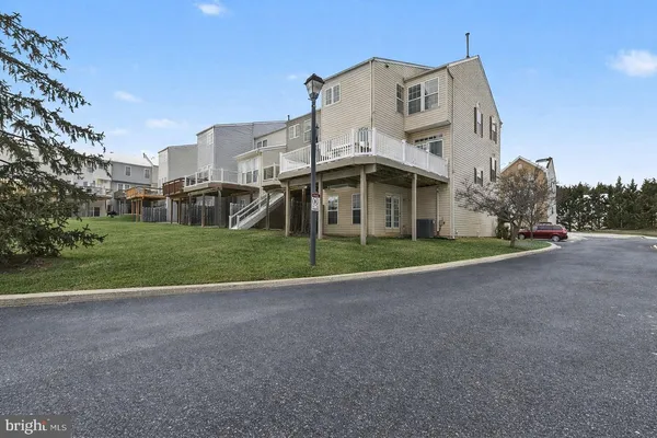 a view of a white house with a big yard and large trees
