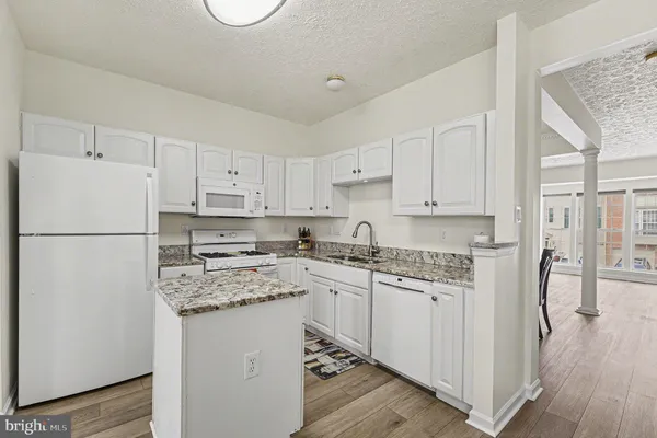 a kitchen with stainless steel appliances granite countertop a refrigerator sink and white cabinets