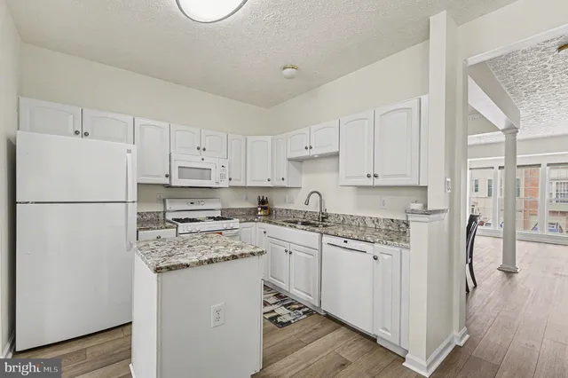 a kitchen with stainless steel appliances granite countertop a refrigerator sink and white cabinets