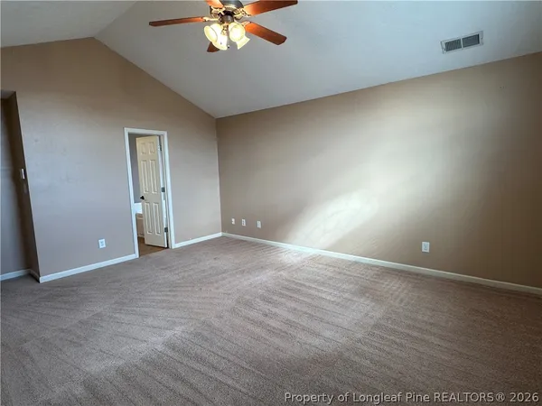 an empty room with a chandelier fan and windows