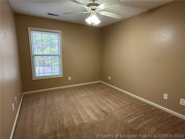 an empty room with a window and a fan
