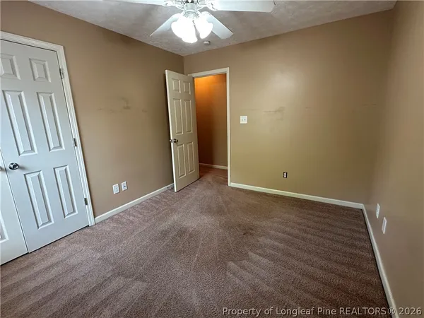 an empty room with chandelier fan and wooden floor