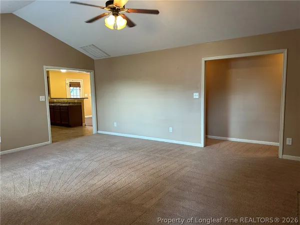 a view of an empty room with a chandelier fan and a window