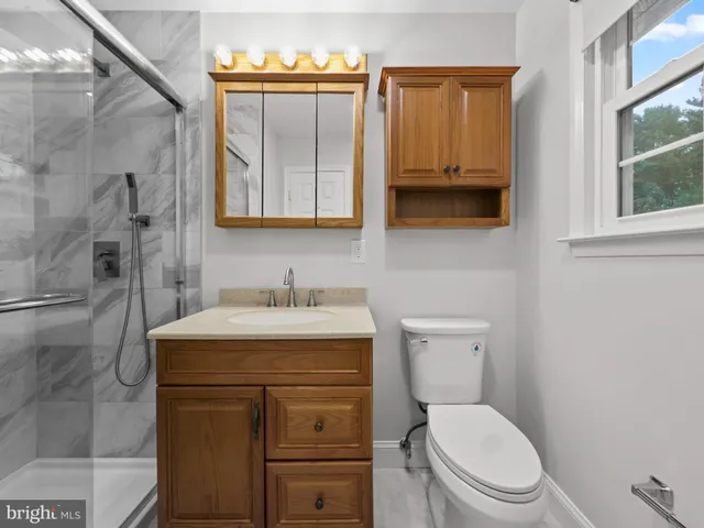 a bathroom with a granite countertop toilet sink and mirror