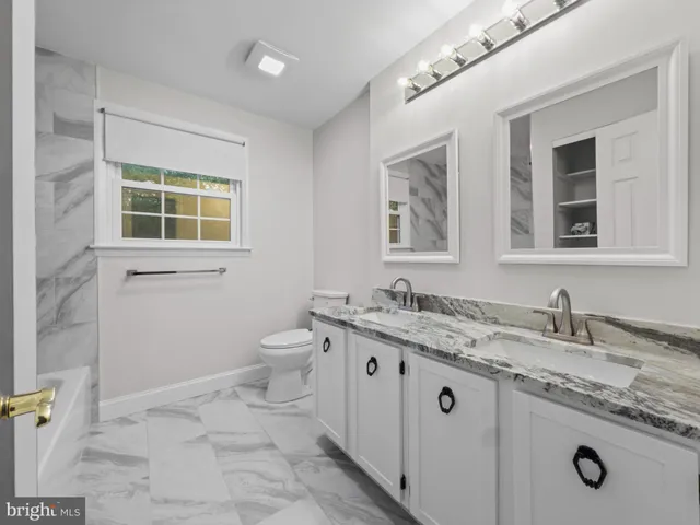 a bathroom with a granite countertop sink a toilet and a mirror
