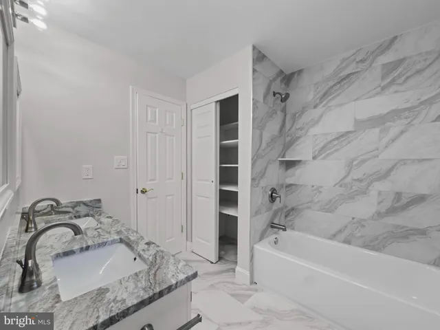 a bathroom with a granite countertop tub sink and mirror