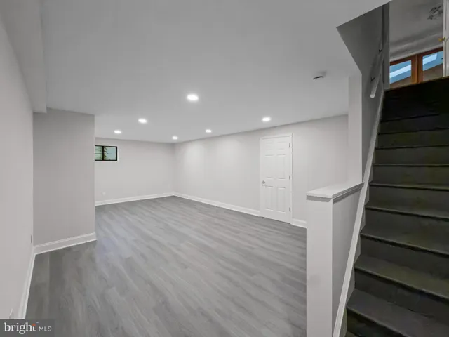 a view of an empty room with wooden floor and stairs