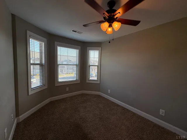 a view of an empty room with window and chandelier fan