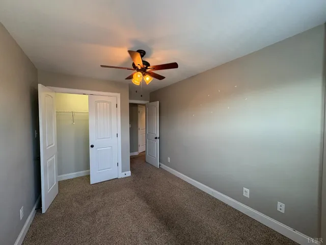an empty room with a ceiling fan and a window