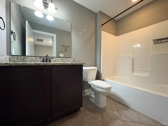 a bathroom with a toilet sink vanity granite and mirror