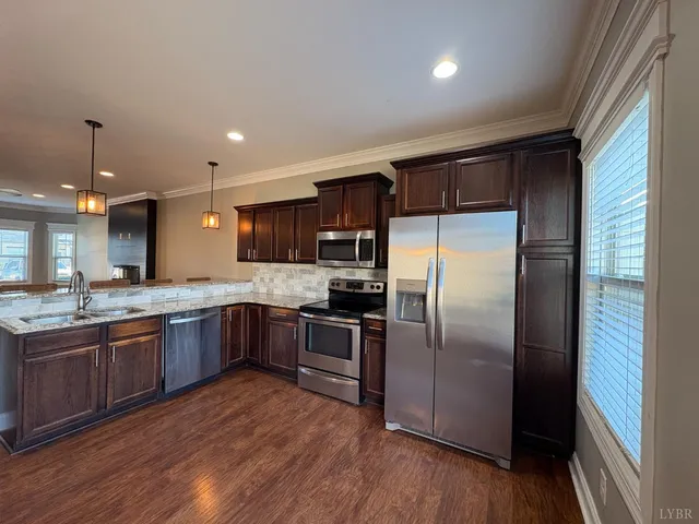 a kitchen with stainless steel appliances granite countertop a refrigerator a sink dishwasher a stove with wooden floors