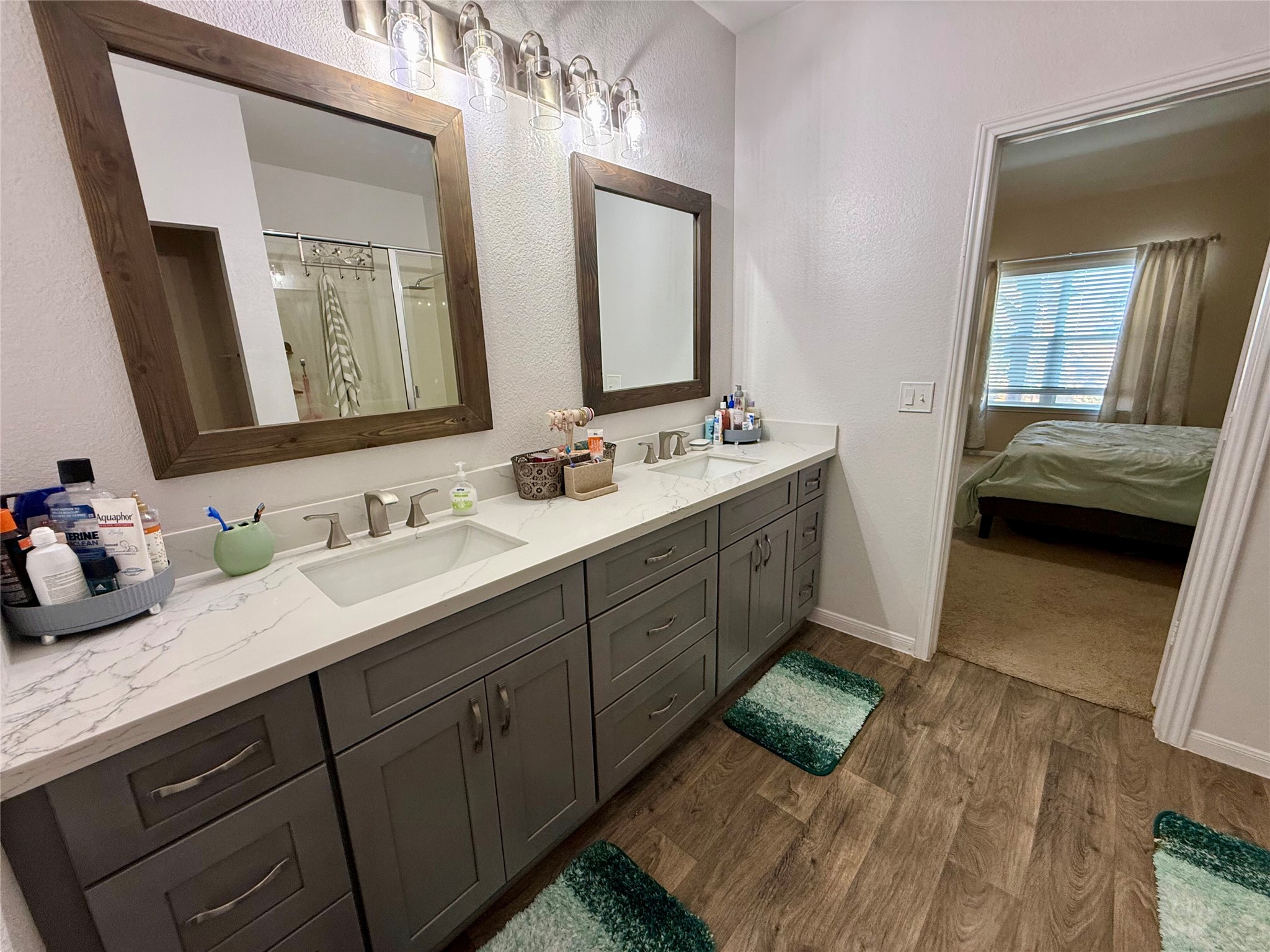 11700 Andesite Road Manor, TX 78653 - Photo 10 of 32 Dual vanity with elegant quartz counters and warm wood-look flooring defines this functional primary bathroom.