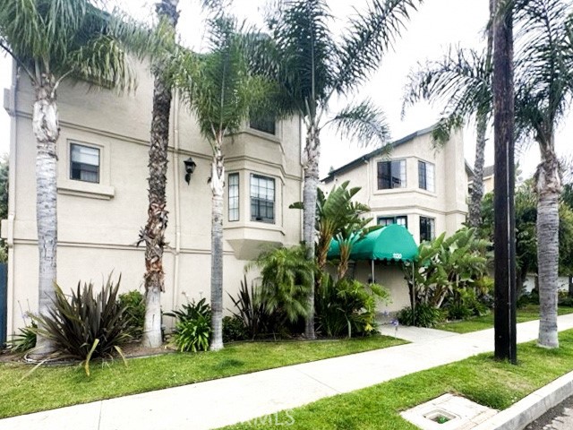 a view of a white house next to a yard with palm trees