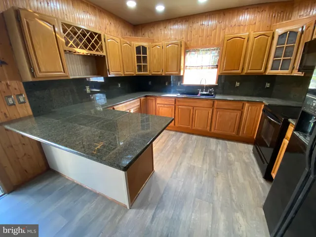 a kitchen with kitchen island granite countertop wooden cabinets a oven a stove and a sink