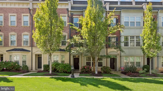 front view of a brick house with a yard and large trees