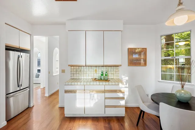 a kitchen with white cabinets and wooden floor