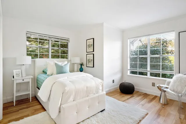 a spacious bedroom with a bed and wooden floor