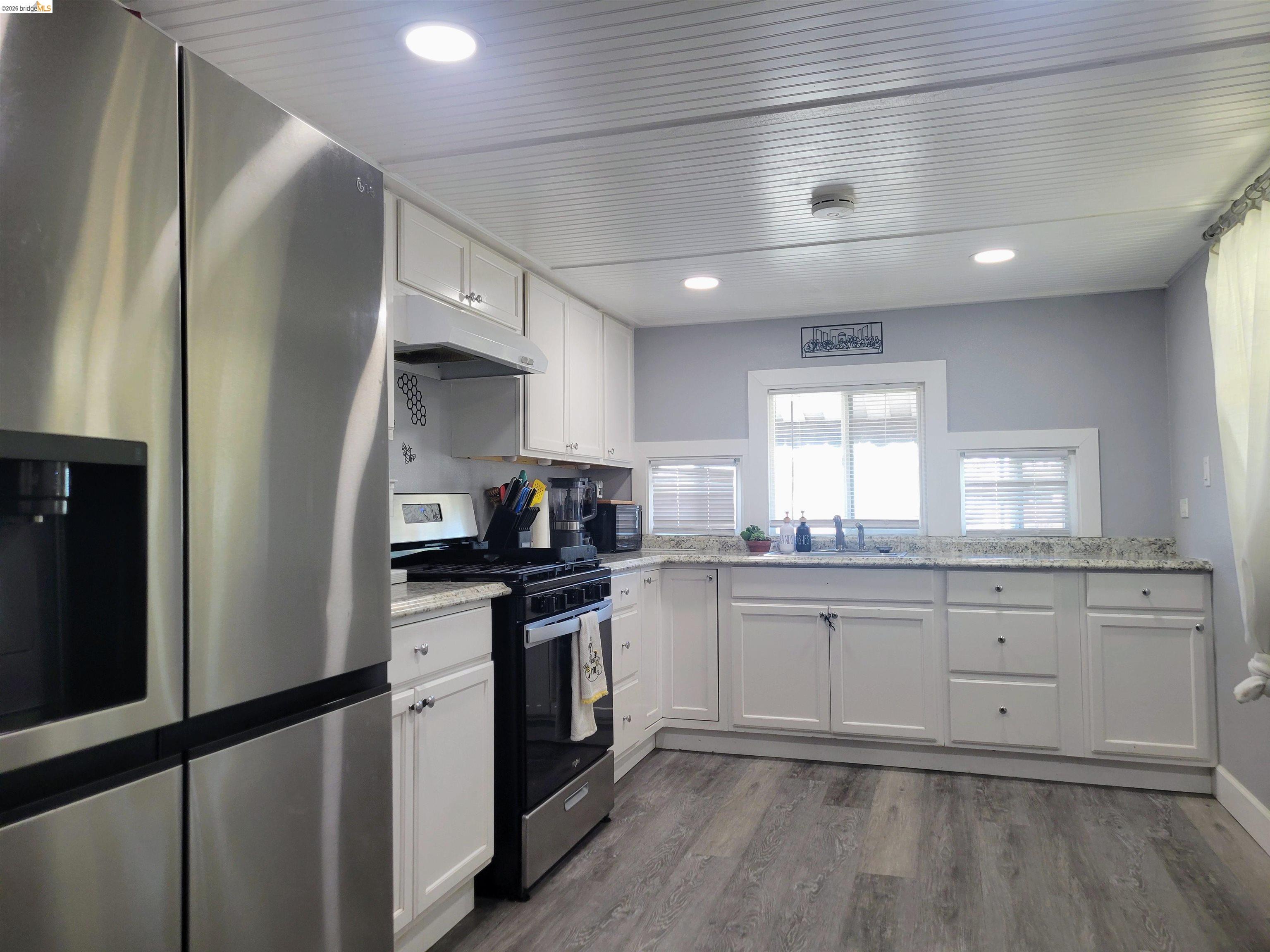 4400 Gateway Road, Unit 38 Bethel Island, CA 94511 - Photo 3 of 5 Kitchen with stainless steel appliances, white cabinetry, dark wood-type flooring, recessed lighting, and light stone counters