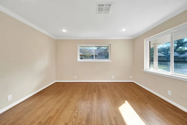 a view of an empty room with window and ceiling fan