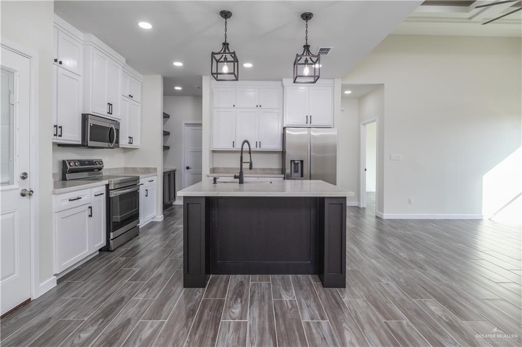 3559 Satelite Street Edinburg, TX 78542 - Photo 5 of 22 a large kitchen with stainless steel appliances kitchen island granite countertop a stove top oven a sink and white cabinets with wooden floor