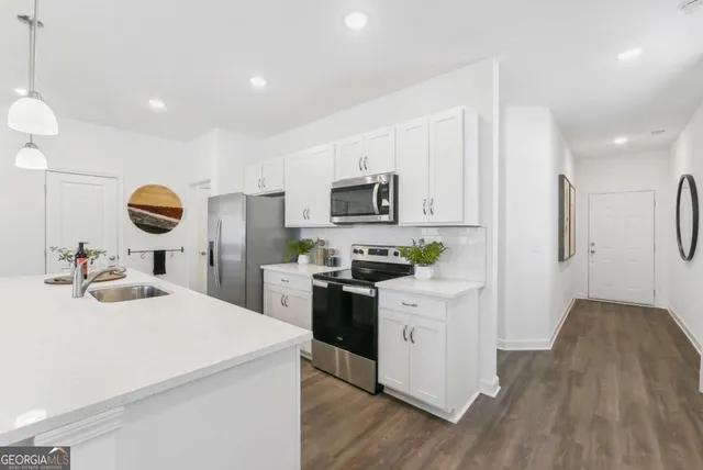 a kitchen with a sink and a stove top oven with wooden floor