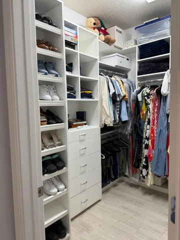 a view of walk in closet with clothes and shoes